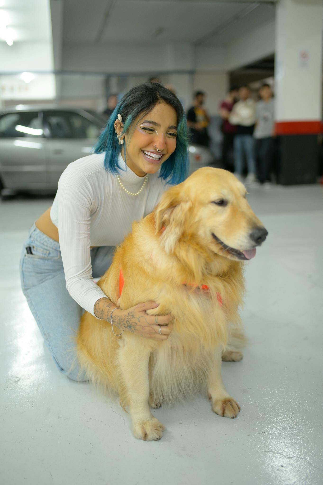 Smiling woman with blue hair and dog in a parking garage. Urban lifestyle.